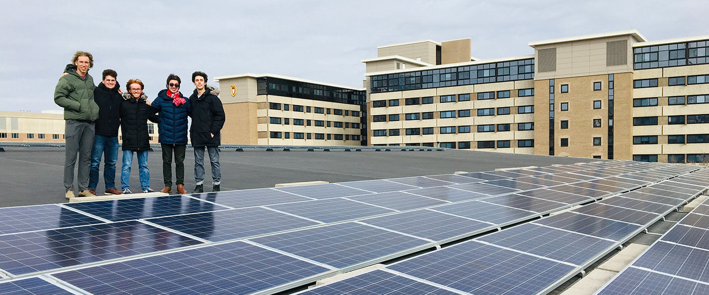 Students pose near solar panels on the Gordon Dining and Event Center rooftop.