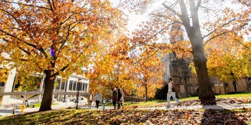 Pedestrians walk along a colorful tree-lined sidewalk on Bascom Hill in fall at the University of Wisconsin-Madison