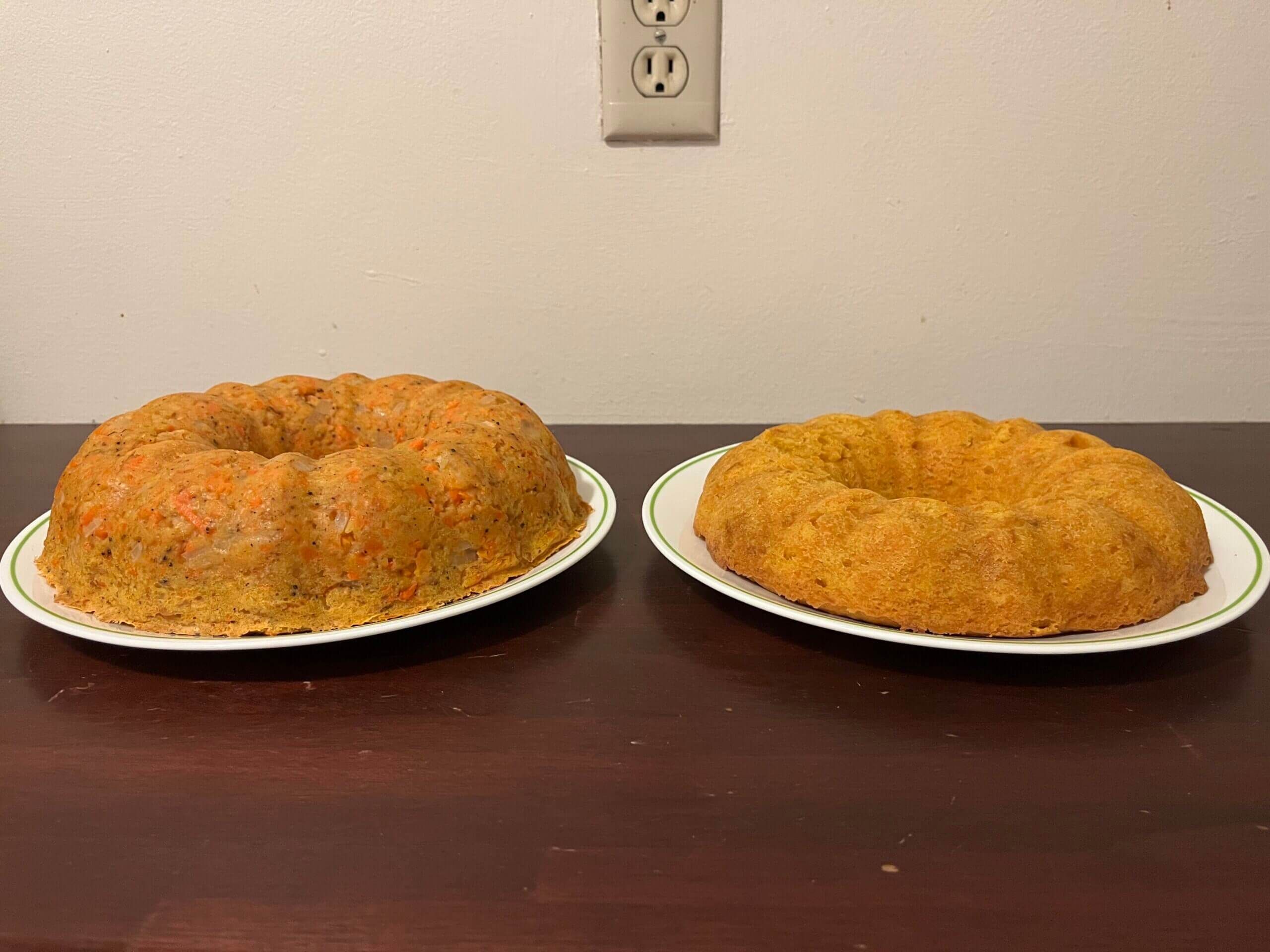 Two golden-orange bundt cakes sit side by side on white plates on a dark brown counter. The one on the left is taller than the one on the right.