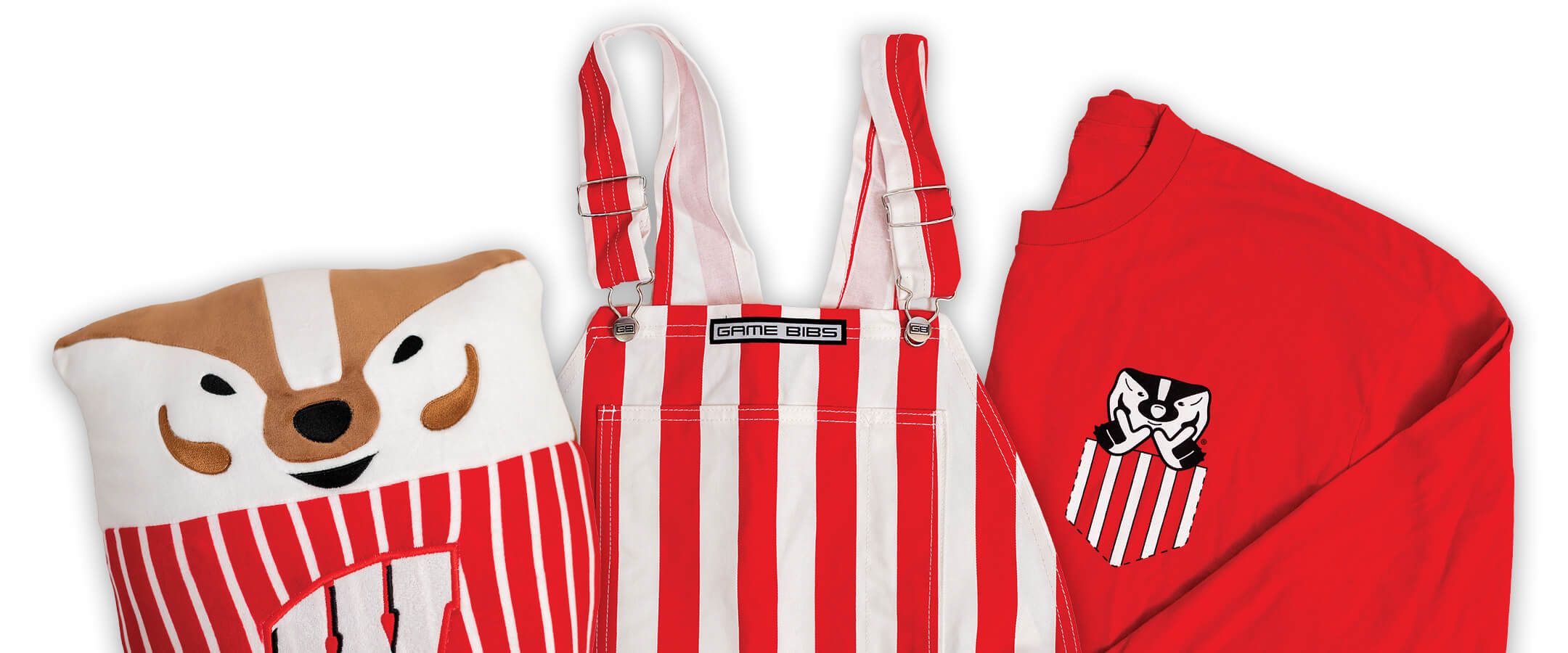 An assortment of University Book Store offerings — from left to right, a Bucky Badger squishmallow, a set of red and white striped overalls, and a red long-sleeve shirt with a decal of a red and white striped pocket with a Bucky Badger head poking out of it — is set against a white background.