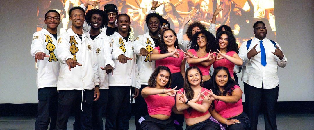 Members of the National Pan-Hellenic Council (NPHC) and the Multicultural Greek Council (MGC) shown posing for a picture on stage.