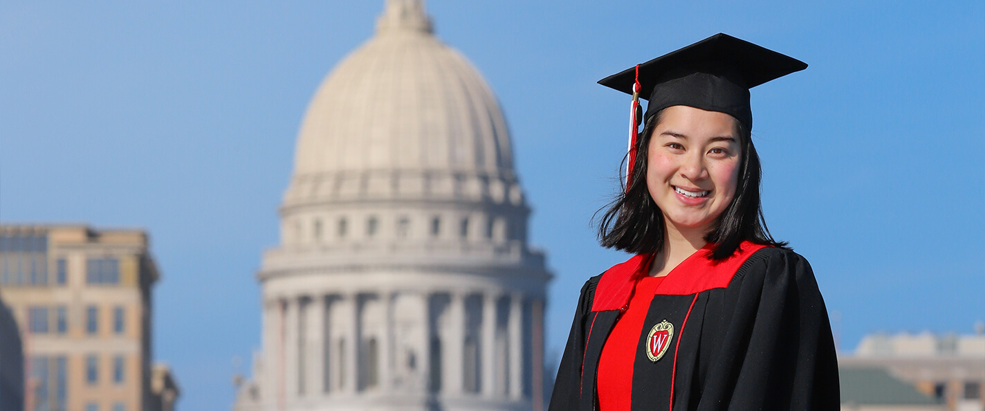 Huang in her cap and gown in front of Wisconsin State Capitol.